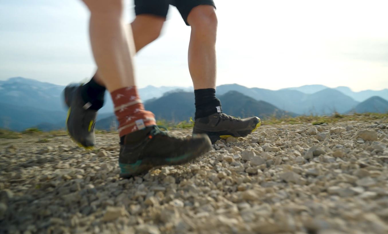 Wandern ohne Steinchen im Schuh – mit norocksocks durch jedes Terrain: Das Foto zeigt zwei Wander:innen mit wunderschönem Ausblick über die Berge. norocksocks sind die ideale Ergänzung für alle, die viel draußen unterwegs sind – beim Wandern, Trekking oder auf Abenteuertouren – und ihre Füße frei von Schmutz halten.